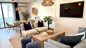 Un salon moderne avec un ensemble de canapés, une table basse et un téléviseur fixé au mur.
