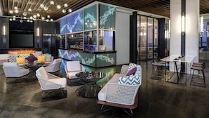 Een moderne lounge met zitplaatsen, een bar en een digitaal scherm.