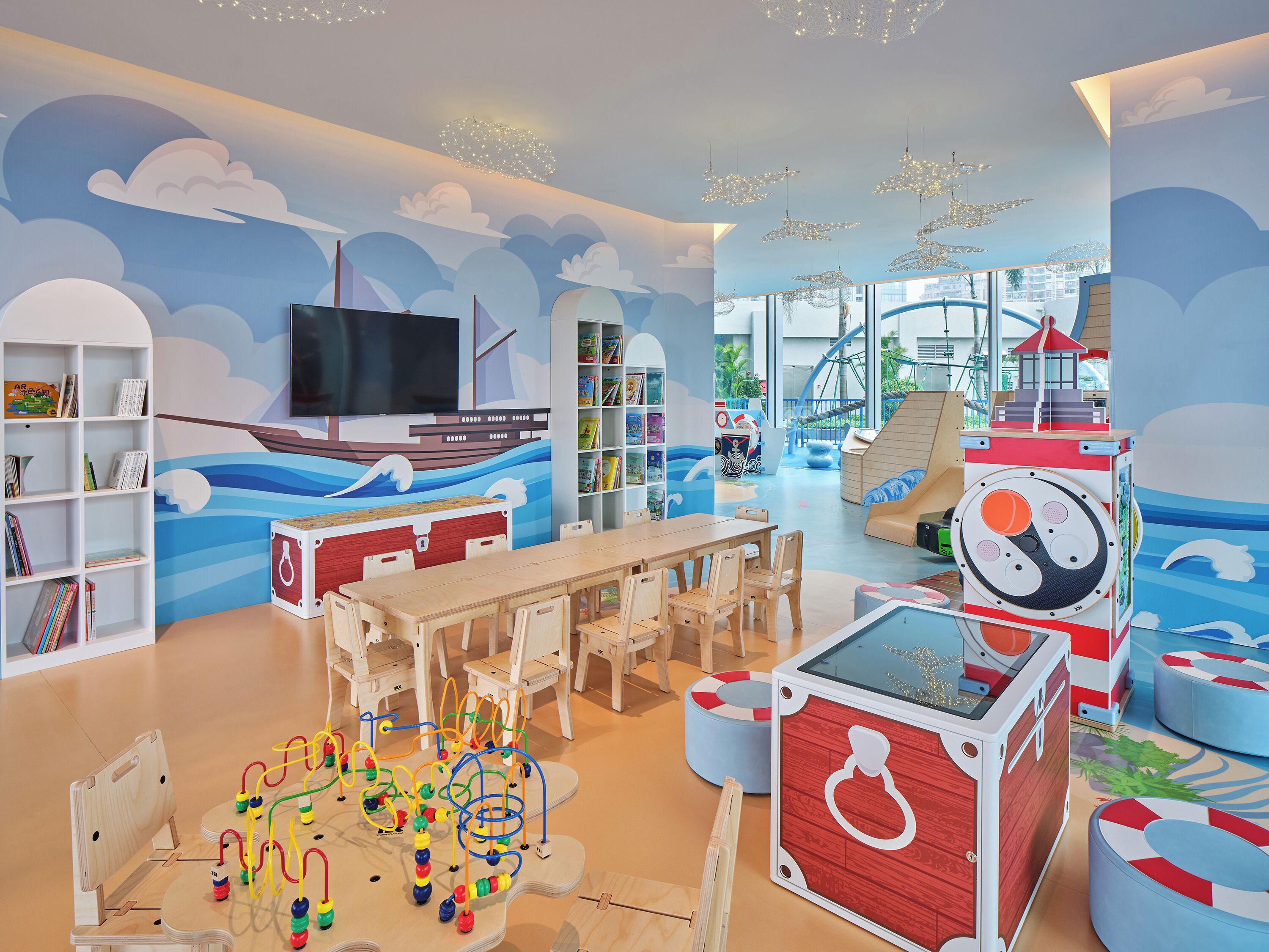 Un área de juegos infantiles con un mural de un barco, un tobogán y una casita.