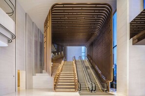 A modern interior with a central staircase flanked by glass railings and a wooden slatted ceiling. - Renaissance Zhuhai (Zhuhai)
