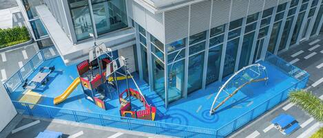Un edificio moderno con un'area giochi per bambini dotata di scivoli e strutture per arrampicarsi.