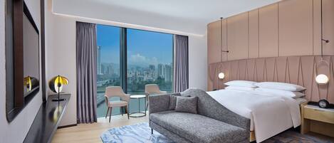 Una habitación de hotel moderna con una cama grande, un sofá, una mesita y una silla.
