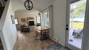Un vaste espace de vie doté d’un plancher en bois, d’une table à manger et d’une cheminée.
