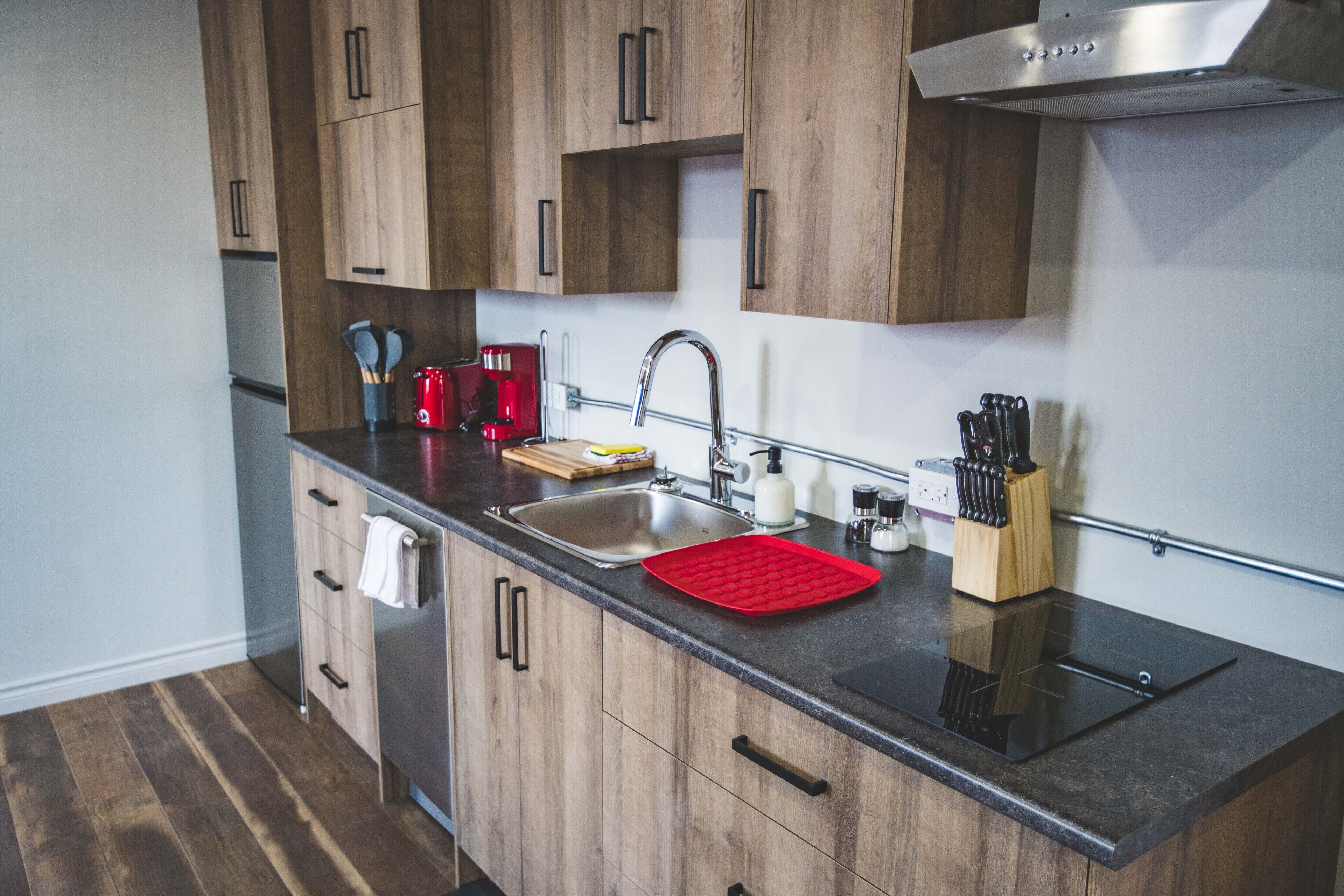 A modern kitchen with wooden cabinets, a stainless steel sink, and a black countertop.