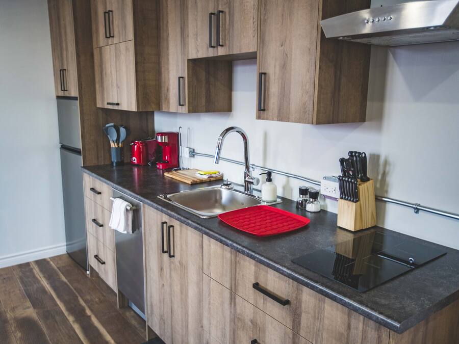 A modern kitchen with wooden cabinets, a stainless steel sink, and a black countertop.