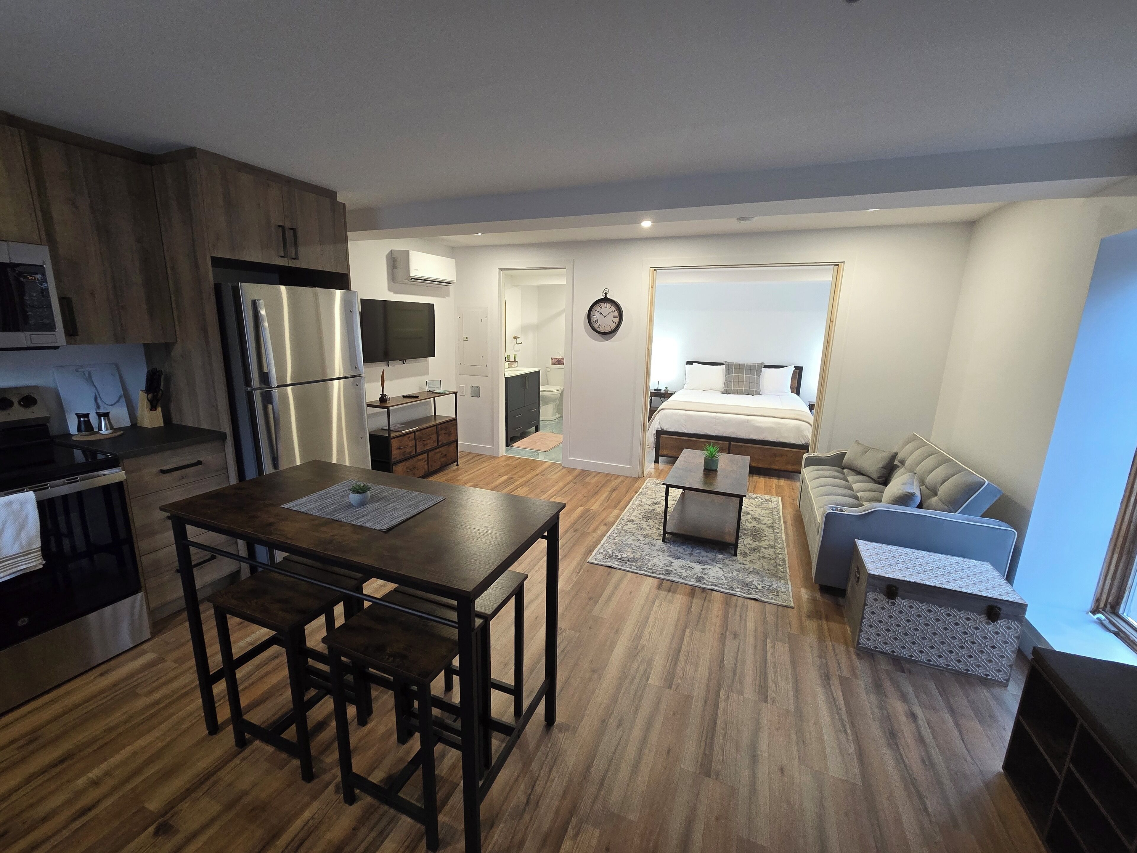 A modern apartment with a kitchen, dining area, and a bedroom.