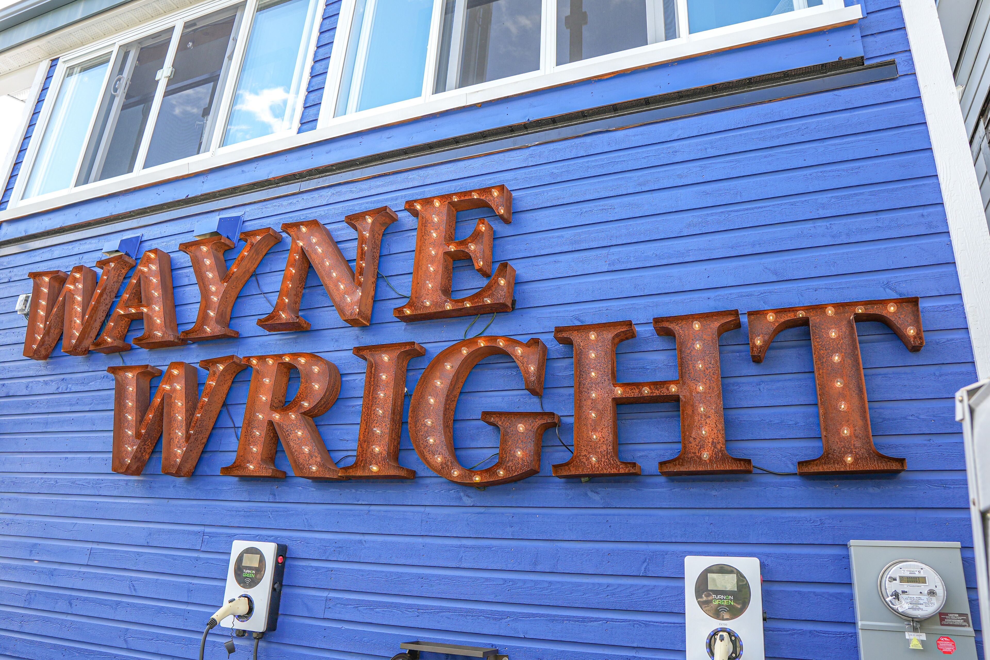 Un edificio con fachada azul y letras iluminadas que dicen "WAYNE WRIGHT".