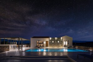 A modern house with a swimming pool, stone walls, and a patio area.
