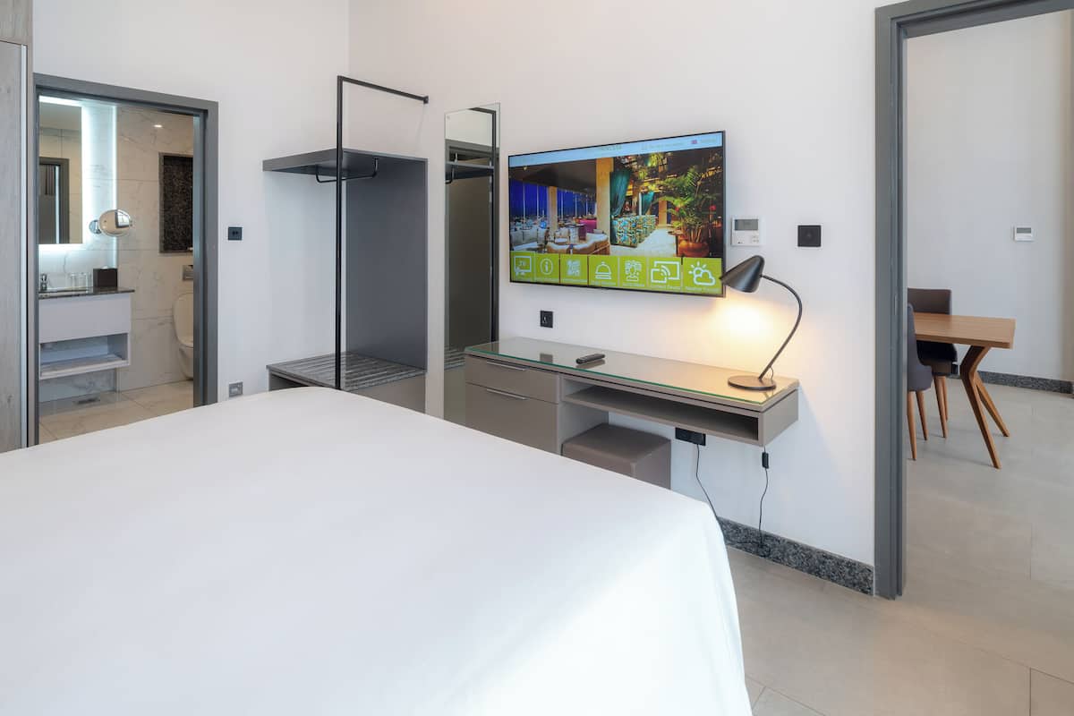 Une chambre d’hôtel moderne équipée d’un lit, d’un bureau et d’un grand écran de télévision affichant le site web de l’hôtel.