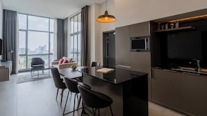 A modern kitchen with a large island, bar stools, and a dining area with a view of the city.