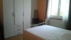 Un dormitorio con cama, armario y ventana.