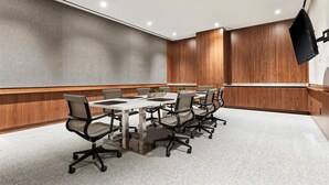 A conference room with a white table, six office chairs, and a wooden accent wall. - Grayson Hotel in the Unbound Collection by Hyatt (New York)