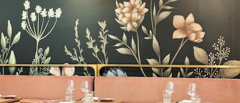 Interior de restaurante con paneles de madera, un mural de flores y un suelo con diseño.