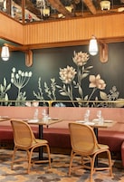 A restaurant interior with wooden paneling, a mural of flowers, and a patterned floor.