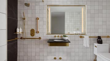 A modern bathroom with a large mirror, a sink, and a shower area.
