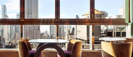 Un moderno comedor con una mesa y sillas, ventanas amplias con vista a la ciudad.