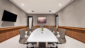 A conference room with a long table, chairs, a TV, and a painting on the wall. - Grayson Hotel in the Unbound Collection by Hyatt (New York)