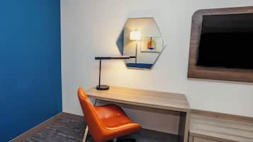 Un espacio de oficina moderno con un escritorio, una silla de oficina naranja, un espejo hexagonal y una lámpara fijada a la pared.