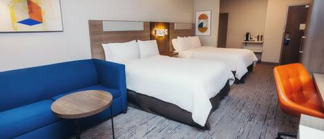 A hotel room with two beds, a blue sofa, a small round table, and an orange chair.