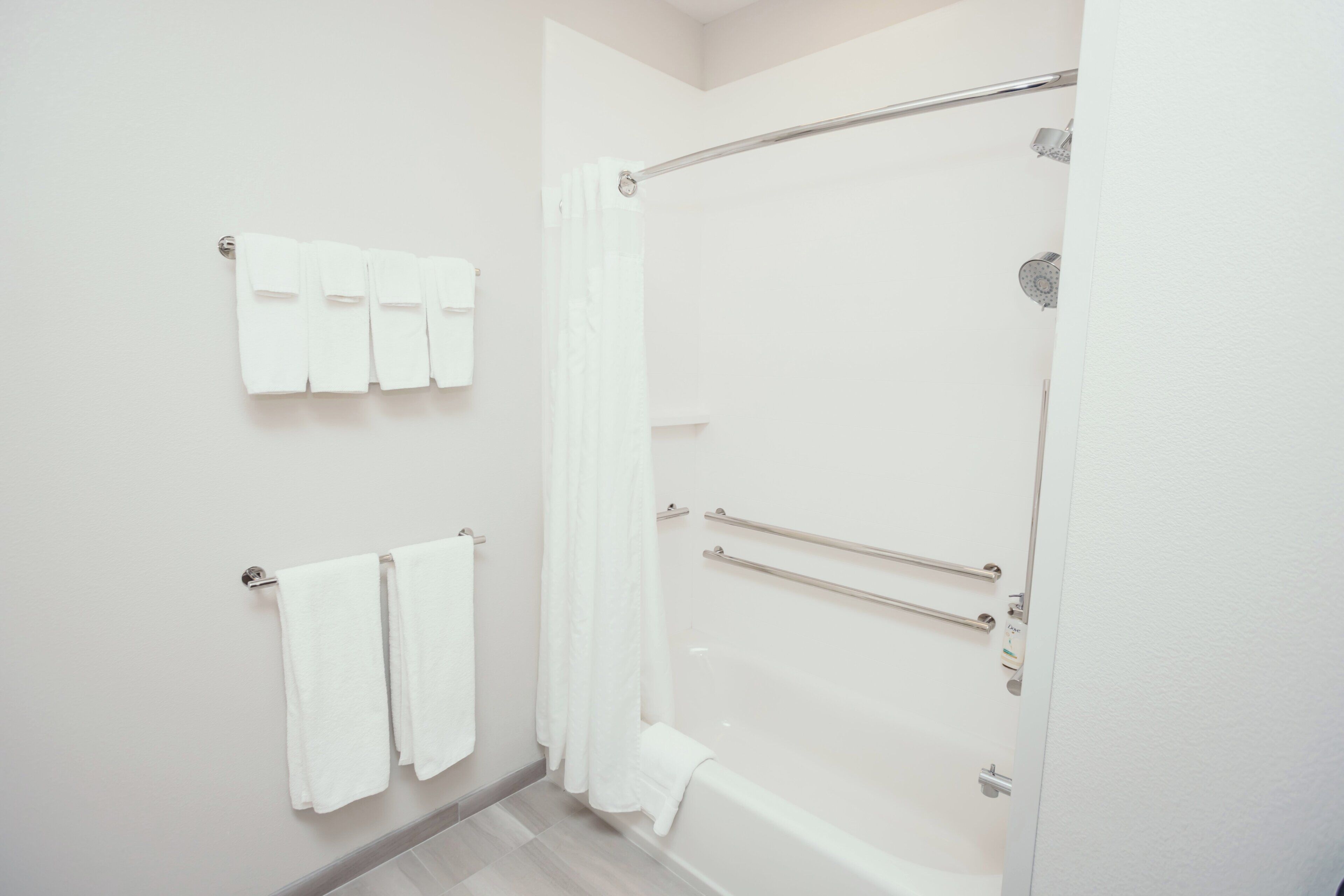 A bathroom with a shower, two towel racks, and a bathtub.
