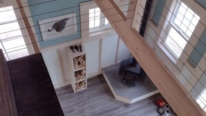 Interior em madeira com escada, lareira e janela.