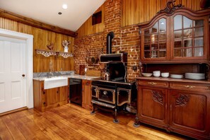 A kitchen with wooden paneling, a brick wall, and a vintage stove.