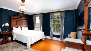 A bedroom with a wooden bed, a nightstand, a lamp, a window with curtains, and a television on the wall. - Stay at the Pre-Civil war home of the Ulysses S. Grant, 18th President of the United States (Galena)