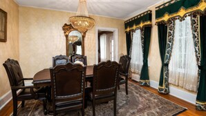A dining room with a large wooden table, ornate chairs, a chandelier, and green curtains with gold trim. - Stay at the Pre-Civil war home of the Ulysses S. Grant, 18th President of the United States (Galena)
