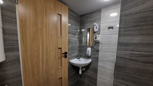 A modern bathroom with a wooden door, a sink, a mirror, and a hairdryer. - Apartment for 5 guests, Krakow Old Town (Kraków)