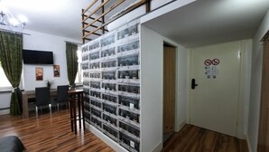 A room with a wooden floor, a desk with chairs, a TV mounted on the wall, and a wall of potted plants. - Apartment for 5 guests, Krakow Old Town (Kraków)
