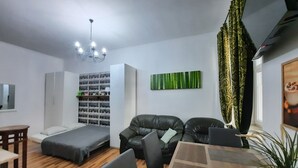 A modern living room with a sofa, a small table, a bookshelf, and a decorative plant. - Apartment for 5 guests, Krakow Old Town (Kraków)