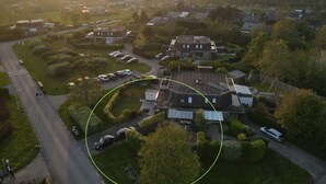 Ett flygbildsbild av ett bostadsområde med hus, parkerade bilar och en slingrande väg.