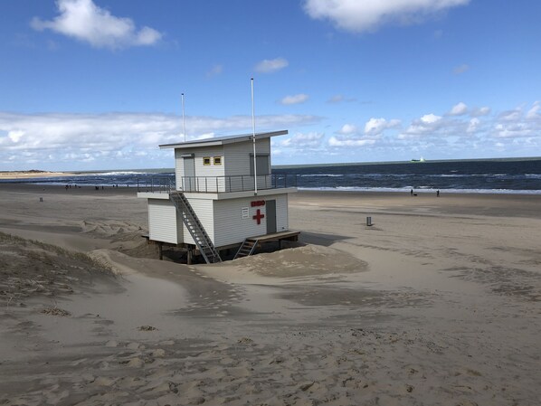 A lifeguard tower on a beach with a clear sky and ocean in the background.