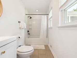 A bathroom with a toilet, a bathtub, and a shower curtain.