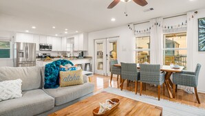 A modern kitchen with stainless steel appliances, a dining area with wicker chairs, and a view through large windows. - Incredible Ocean Sunrise Views, Sleeps 12, Experienced VRBO Premier 5 STAR Host (Freeport)