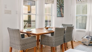 A dining area with a wooden table, wicker chairs, white curtains, and a painting on the wall. - Incredible Ocean Sunrise Views, Sleeps 12, Experienced VRBO Premier 5 STAR Host (Freeport)