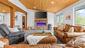 A cozy living room with a stone fireplace, leather sofas, and a wooden ceiling.