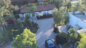 A residential property with a covered patio, a car parked in the driveway, and surrounding greenery. - Complesso di ville con piscina (porto cesareo)