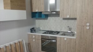 A compact kitchen with wooden cabinets, a stainless steel sink, and a built-in oven. - Complesso di ville con piscina (porto cesareo)