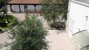 A building with a tiled roof, a fenced area, and a garden with various plants. - Complesso di ville con piscina (porto cesareo)