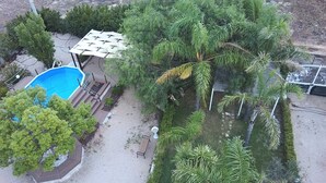 An aerial view of a residential area with a swimming pool, a covered patio, and various trees. - Complesso di ville con piscina (porto cesareo)