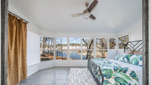 A bedroom with a bed, a ceiling fan, a view of a lake, and a window with curtains. - Cheerful & Stylish 4 Bedroom Lake-Side House (Hot Springs)
