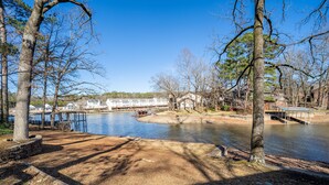 A lakeside park with a dock, trees, and a building in the background. - Cheerful & Stylish 4 Bedroom Lake-Side House (Hot Springs)