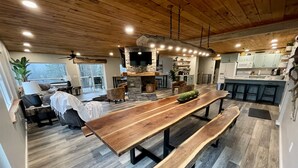 Een ruime keuken met een lange houten tafel, een stenen openhaard en een modern keukenblok.