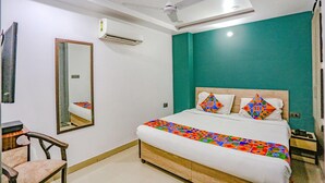 Ein Schlafzimmer mit einem Bett, einem Deckenventilator, einer Klimaanlage, einem Spiegel und einer türkis farbenen Akzentwand.