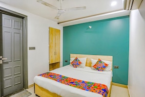 A bedroom with a bed, a ceiling fan, a door, and a wall with a teal color. - Fabexpress Rama (New Delhi)