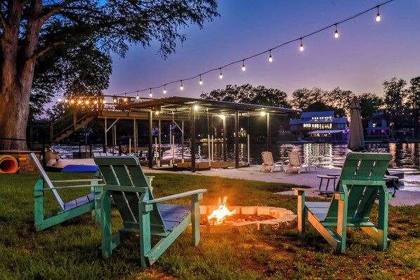 A lakeside deck with outdoor seating and a fire pit.