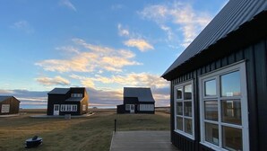 A coastal property with a wooden deck leading to a building with large windows.