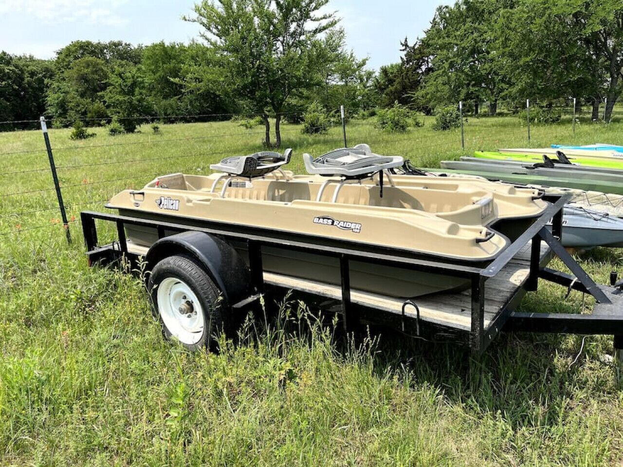 A boat trailer with a boat on it, parked in a grassy area.