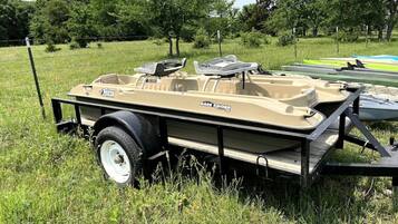 A boat trailer with a boat on it, parked in a grassy area.
